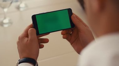 Zarif iş adamı damat yeşil ekranlı akıllı telefonunu izliyor, 4K ağır çekim.