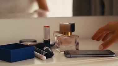 Makyaj masasından akıllı telefonu alan bir kadın, 4K ağır çekim.