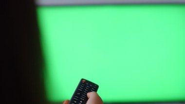 Yeşil ekranlı televizyona karşı uzaktan kumanda kullanan kadın, bakış açısı 4k