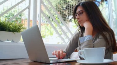 Güzel, başarılı bir iş kadını laptopuyla kafede kahve içiyor, dizüstü bilgisayarda çalışıyor ve telefon kullanıyor..
