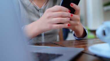 Güzel, başarılı bir iş kadını laptopuyla kafede kahve içiyor, dizüstü bilgisayarda çalışıyor ve telefon kullanıyor..