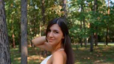 Güzel esmer bir kızın parkta kamerayla flört edişinin portresi, 4K ağır çekim.