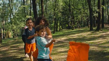 Güneşli bir günde parkta çekiştirmece oynayan çocuklar, 4K ağır çekim.