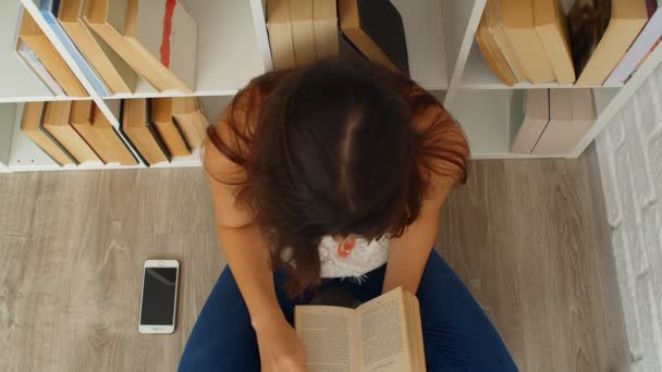 若いです女性読書A本に座って床に家 上のビュー4K — ストック動画