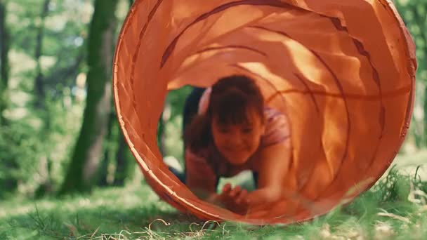 小女孩爬到公园里的儿童玩具隧道里 — 图库视频影像