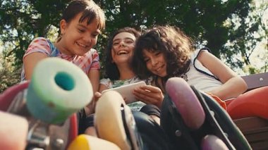 Parkta akıllı telefonlara bakan üç kız arkadaş. Okul arkadaşı kavramı. 4k pov