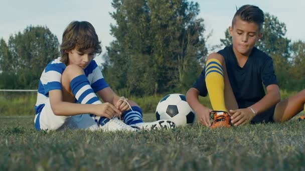 若いサッカー選手はフィールドでのトレーニングの前に自分の靴をバックル 4Kスローモーション — ストック動画