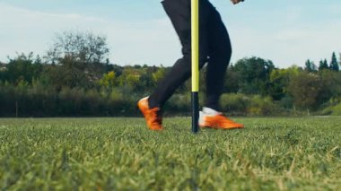 Tanınmayan adam sahada futbol topuyla antrenman yapıyor.