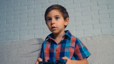 5 yaşındaki çocuk oyun konsolu oynuyor, eğleniyor, gülüyor, joystick 'i evde tutuyor, 4k