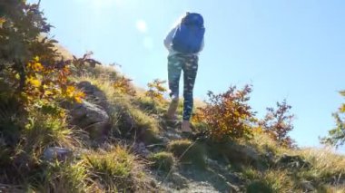 Güneşli bir sonbahar gününde dağda yürüyen bir kadın turistin kamera görüntüsü, 4K
