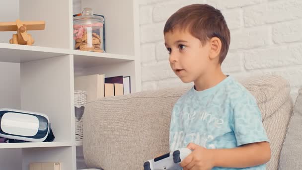 5歳の少年は ビデオゲームコンソールをプレイし 家でジョイスティックを保持し 楽しみを持っている — ストック動画