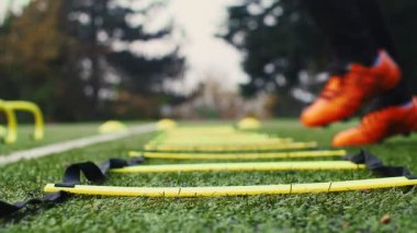 Futbol çeviklik eğitim ekipmanları. Çeviklik merdiveni olan profesyonel bir futbolcu. 4k ağır çekim
