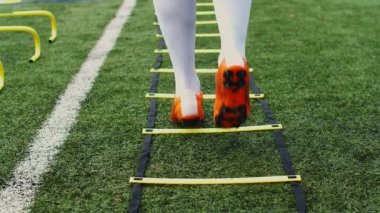 Futbol çeviklik eğitim ekipmanları. Çeviklik merdiveni olan profesyonel bir futbolcu. 4k ağır çekim