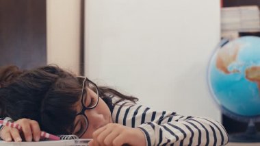 Gözlüklü tatlı beyaz kız ödevinde uyuyakalmış ve uyanmış, 4k.