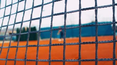 Tenis topuyla tenis oynayan kız tenisçi Clay Court 'ta, net önde, dolly, 4k, yavaş çekim 75 fps