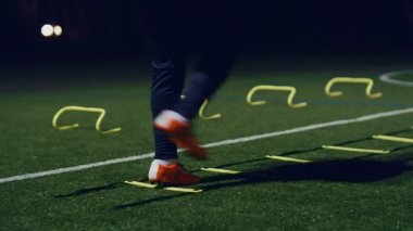 Futbol çeviklik eğitim ekipmanları. Çeviklik merdiveni ve geceleri engelli profesyonel futbolcu, 4k ağır çekim.