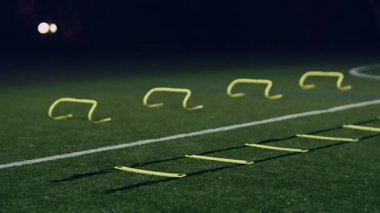 Futbol çeviklik eğitim ekipmanları. Profesyonel futbolcu, çeviklik merdiveni ve geceleri engelli, 4k ağır çekim.