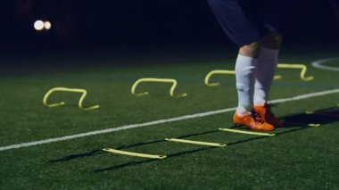 Futbol çeviklik eğitim ekipmanları. Profesyonel futbolcu, çeviklik merdiveni ve geceleri engelli, 4k ağır çekim.