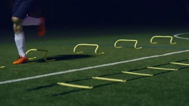 Futbol çeviklik eğitim ekipmanları. Profesyonel futbolcu, çeviklik merdiveni ve geceleri engelli, 4k ağır çekim.
