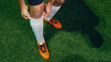 Profesyonel futbolcu, maç başlamadan önce çoraplarını ayarlar, 4K ağır çekim.