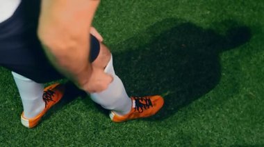 Profesyonel futbolcu, maç başlamadan önce çoraplarını ayarlar, 4K ağır çekim.