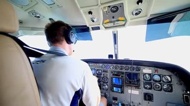 Küçük bir uçağı uçuran bir erkek pilotun kokpit arka görüntüsü.