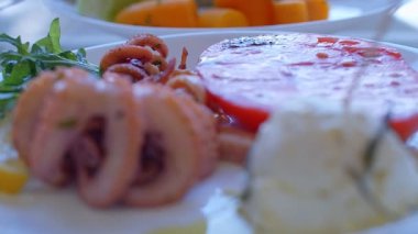 Ahtapot, salata, domates ve peynirli bir tabak Akdeniz yemeği.