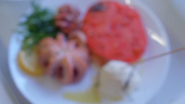 Ahtapot, salata, domates ve peynirli bir tabak Akdeniz yemeği.