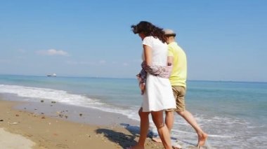 Romantik tatilde olan genç bir çift boş bir sahilde ağır çekimde yürüyor.