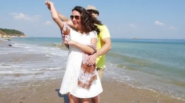 Genç çift romantik bir tatilde boş bir sahilde dans ediyor, ağır çekimde.