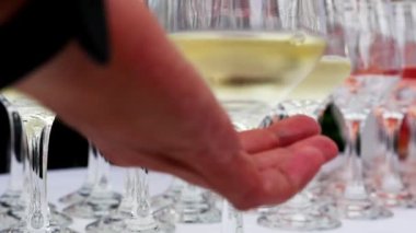 Şampanyalı bir bardak alan bir erkek. Beyaz bir masa örtüsünün üzerinde içki şişeleriyle bir sıra şarap kadehini zarif bir şekilde sıraya dizdim.