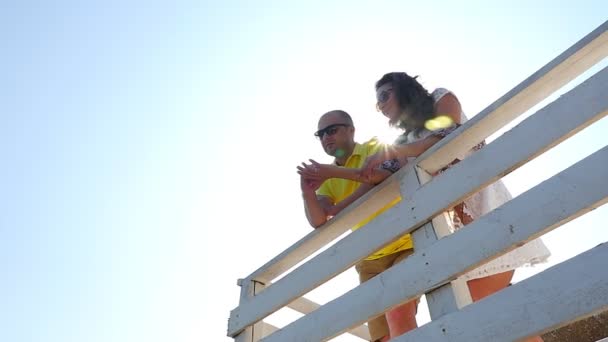 低角度年轻夫妇在白色楼梯上俯瞰着海滩 动作缓慢 — 图库视频影像