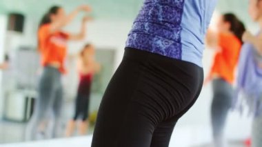 Dans fitness sınıfı Zumba dans eden güzel kadınlar koreografi hareketlerinden zevk alıyorlar bir spor salonunda bir eğitmenle, 4k ağır çekim