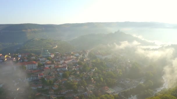 ブルガリアのヴェリコ タルノヴォ市 朝の霧の中で古い家や有名なツァレベツ要塞のトップビュー — ストック動画