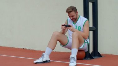Basketbol Fan Reaction Concept - Basketbol kıyafetli heyecanlı basketbolcu akıllı telefondan en sevdiği takımı izliyor, 4K ağır çekim