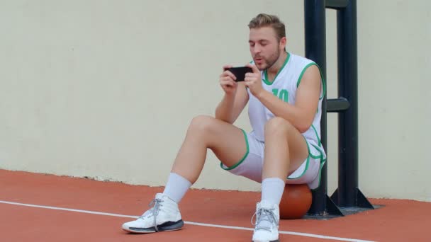 篮球迷反应概念 篮球队里兴奋的篮球员在智能手机上观看他最喜欢的球队 4K慢动作 — 图库视频影像