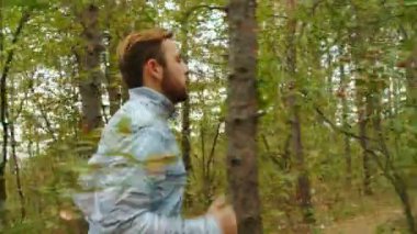 Sonbahar parkında koşan genç bir adamın kamera görüntüsü, ahşap, orman, 4k ağır çekim.