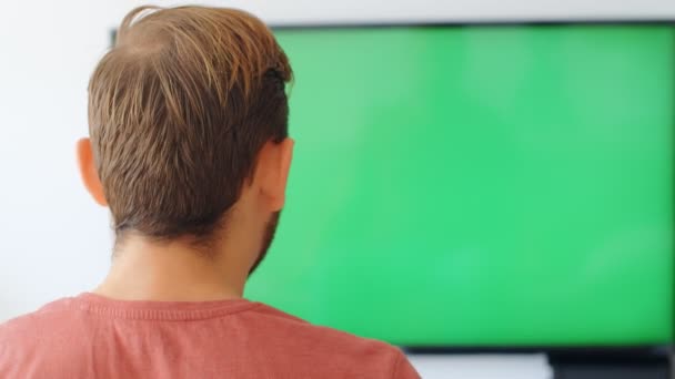 スポーツファンの反応コンセプト 自宅でテレビの緑の画面上で彼のお気に入りのチーム 選手を見て怒って失望したスポーツファンのバックビュー 4Kスローモーション — ストック動画