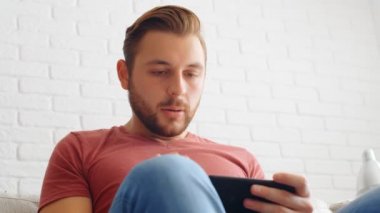 Sports Fan Reaction Concept - Hayal kırıklığına uğramış sporsever hayranı evinde akıllı telefondan en sevdiği takım / oyuncuyu izliyor, 4k ağır çekim