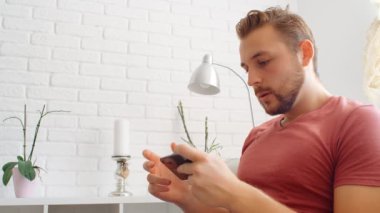 Sports Fan Reaction Concept - Hayal kırıklığına uğramış sporsever hayranı evinde akıllı telefondan en sevdiği takım / oyuncuyu izliyor, 4k ağır çekim