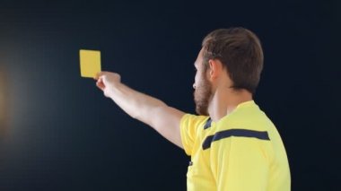 Siyah arka planda futbol hakemi penaltı sarı kartını gösteriyor, 4k ağır çekim.