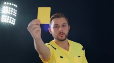 Siyah arka planda futbol hakemi penaltı sarı kartını gösteriyor, 4K