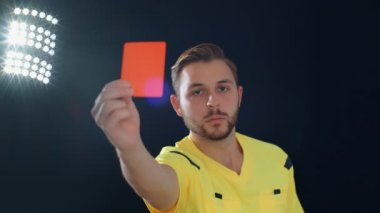 Siyah ekrandaki futbol hakemi kırmızı kart 4K gösteriyor.