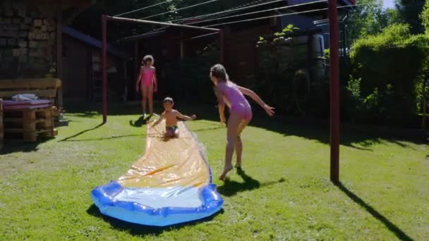 快乐的小高加索孩子们在花园里的滑水上玩得很开心 为孩子们准备凉爽的暑假 水上运动 — 图库视频影像
