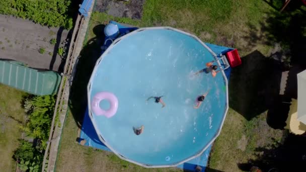 庭のスイミングプールで楽しんでいる幸せな小さな白人の子供たち 最上階だ 子供や子供のための涼しい夏の休日 水の上のゲーム ピンクのドーナツ — ストック動画
