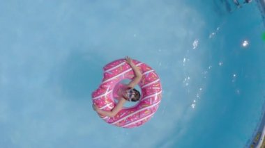 Küçük beyaz çocuklar bahçede yüzme havuzunda eğleniyorlardı. Üst Manzara. Çocuklar ve çocuklar için serin yaz tatilleri. Suda oyunlar. Pembe donat. 4k