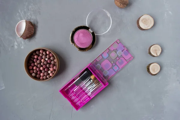 A set of pink makeup brushes and cosmetics