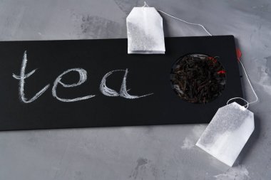 Üzerinde çay yazılı siyah bir plaka olan gri bir arkaplanda çay.