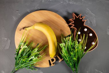 Muz, yuvarlak tepsi ve lamba gri bir arka plan üzerinde ananas şeklinde