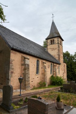 Roth an der Our, Almanya'daki St. Peter Kilisesi - Tapınak Şövalyeleri'nin eski bir kilisesi, dramatik bulutlu gökyüzü altında kısmi yaz dış görünümü
